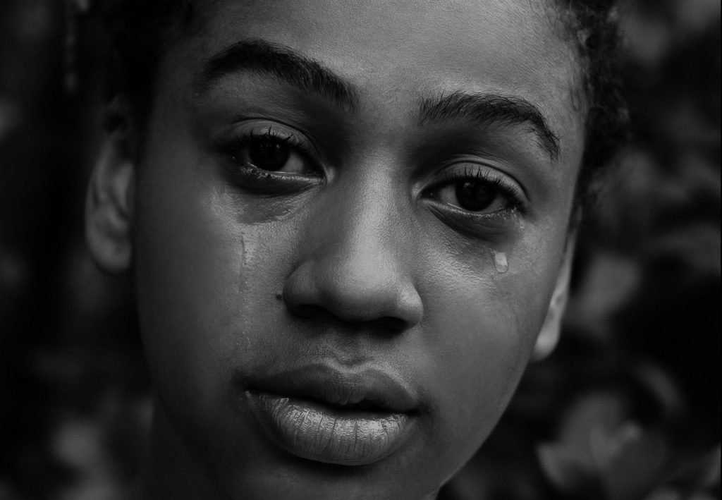 Eine Frau schaut mit starkem Blick in die Kamera, während ihr Tränen über die Wangen laufen